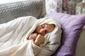 Woman slleping, lying on sofa, wrapped in wool white plaid, tries to warm herself, having flu symptoms, feels cold, indoor. Cold, Royalty Free Stock Photo