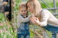 A woman with a small daughter make a selfie in a greenhouse with flowers.