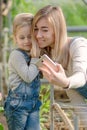 A woman with a small daughter make a selfie in a greenhouse with flowers.