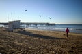 Woman with a small dog enjoying the sandy beach with a lifeguard tower and Boscombe pier