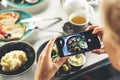 Woman with smart phone taking picture of food at restaurant Royalty Free Stock Photo