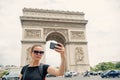 Woman with smartphone at arch monument in paris, france. Woman make selfie with phone at arc de triomphe. Vacation and Royalty Free Stock Photo