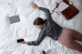 Exhausted woman with smartphone and documents sleeping fully dressed on bed at home, above view Royalty Free Stock Photo