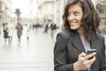 Woman with smartphone in hands walking on street