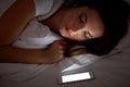 Woman with smartphone sleeping in bed at night Royalty Free Stock Photo