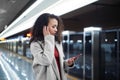 woman with a smartphone typing SMS standing on the subway platform. Royalty Free Stock Photo