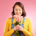 Woman, smell roses and gift in studio, smile and excited for celebration, birthday or party by pink background. Japanese