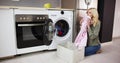 Woman Smelling Clean Clothes Near The Electronic Washer Royalty Free Stock Photo