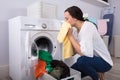 Woman Smelling Cleaned Yellow Cloth Near Washing Machine