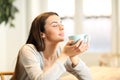 Woman smelling coffee aroma at home