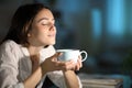 Woman smelling decaffeinated coffee in the night