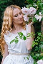 Woman smelling and enjoying beautiful roses flowers beautiful sunny spring day. Smiling young woman posing with blossom Royalty Free Stock Photo