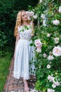 Woman smelling and enjoying beautiful roses flowers beautiful sunny spring day. Smiling young woman posing with blossom Royalty Free Stock Photo
