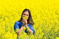 Woman smelling yellow flowers in rapeseed field