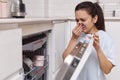 woman smells terrible smell coming from dishwasher machine Royalty Free Stock Photo