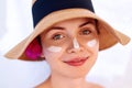 Woman smile applying sun cream on face. Skincare. Body Sun protection. sunscreen. Female in hat smear moisturizing lotion on ski