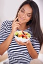 Woman, smile and fruit bowl and thinking, natural nutrition and healthy organic food. Happy, female person with snack Royalty Free Stock Photo