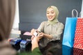 woman smiles as she give credit cards to cashier while paying