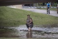 Woman smiles as she wades through filthy  flood water under underpass by Arkansas River during 100-yr flood Royalty Free Stock Photo