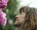 A Woman Smiles Up at Pink Roses