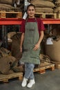 Woman Smiling at Camera and Wearing Apron Standing in Coffee Shop Warehouse Royalty Free Stock Photo
