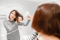 Woman smiling and drying her hair with hairdryer near the mirror in the bathroom Royalty Free Stock Photo