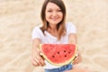 Young woman smiling face out of focus. focus on hands holding watermelon piece. girl in white t-shirt shallow depth of field photo