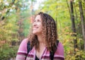 Woman smiling and hiking through forest in autumn, curly hair an