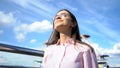 Woman smiling looking up to blue sky, taking deep breath, celebrating freedom