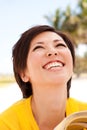 Asian woman smiling and reading the Bible at the Beach