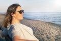 Woman smiling and relaxing at the sea dressed in peace sitting on the bench on the beach. Sunglasses Royalty Free Stock Photo