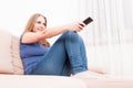 Woman smiling relaxing on sofa holding remote control Royalty Free Stock Photo