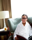 Woman smiling sitting in chair reading.