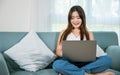 woman smiling sitting relaxing on sofa using laptop in living room at home Royalty Free Stock Photo
