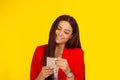 Woman smiling while texting on smartphone isolated on yellow