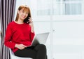 Woman smiling using mobile phone call director to team during working with laptop computer at home office Royalty Free Stock Photo