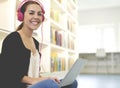 Woman smiling wearing pink headphones in library