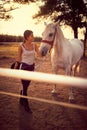 Woman smiling at a white horse. fun on countryside,  golden hour. Freedom nature concept Royalty Free Stock Photo