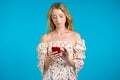 Woman sms texting, using app on smartphone. Pretty girl with blonde hair surfing internet with mobile phone. Blue studio Royalty Free Stock Photo