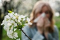 Woman sneezing and blowing nose in blooming park Royalty Free Stock Photo