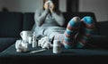 Woman sneezing and blowing nose with tissue and handkerchief. Sick and ill person with flu, cold medicine and woolen socks.