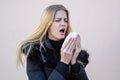 Woman sneezing with closed eyes when cold weather