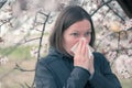 Woman sneezing in front of blooming cherry tree in spring Royalty Free Stock Photo