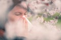 Woman sneezing in front of blooming cherry tree in spring Royalty Free Stock Photo