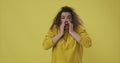 Woman sneezing over yellow background