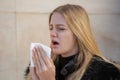 Woman sneezing in winter in black jacket