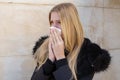 Woman sneezing in winter in black jacket