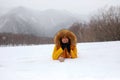 Woman in the snow white with snowing in the forest and mountain background.