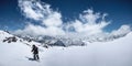 Woman snowboarder freerider climb up the fresh snow riding backcountry. Peaks of mountains and blue sky with clouds in Royalty Free Stock Photo