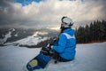 Woman snowboarder in winter at ski resort sits Royalty Free Stock Photo